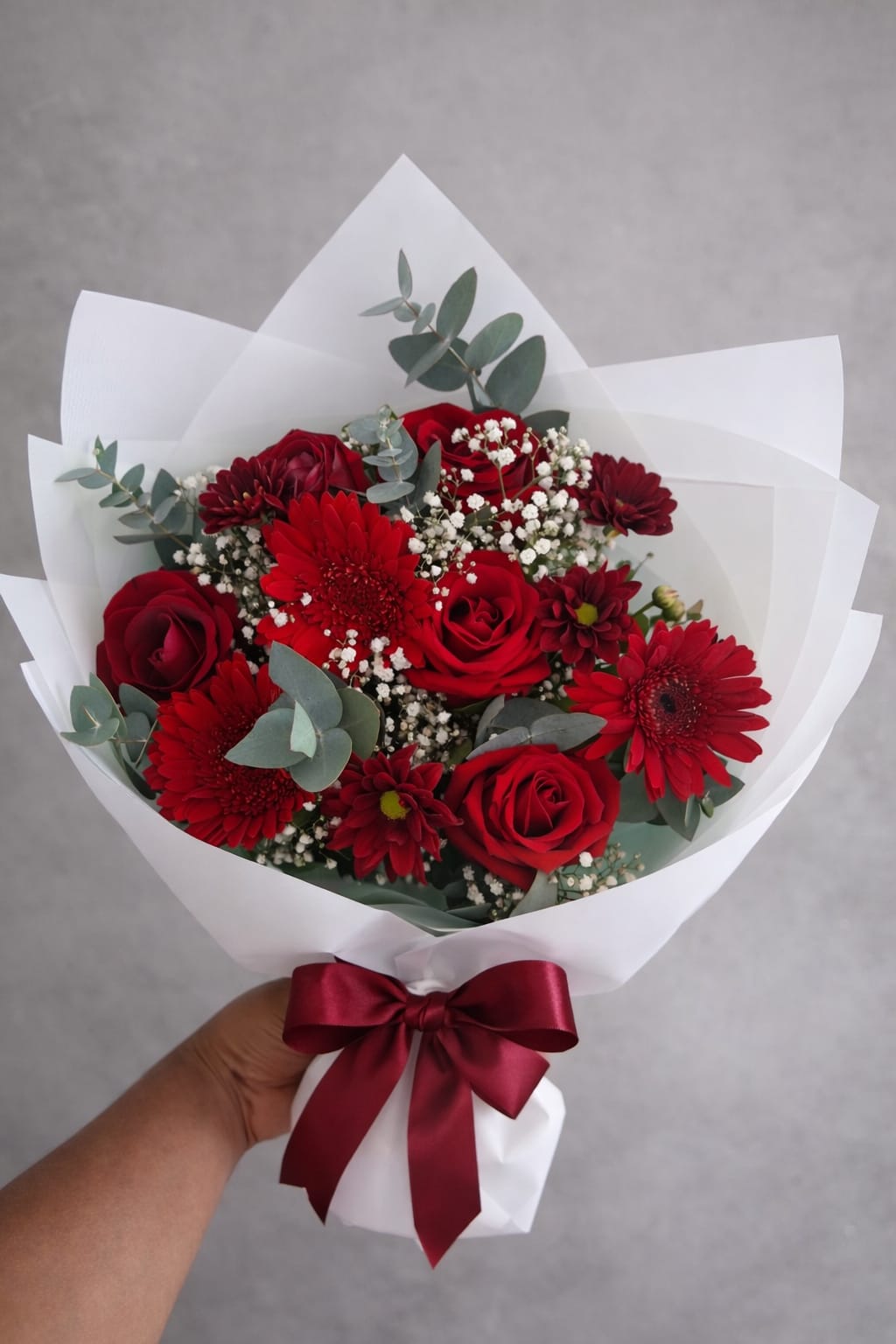 Buquê de rosas e gerberas vermelhas com laço bordô